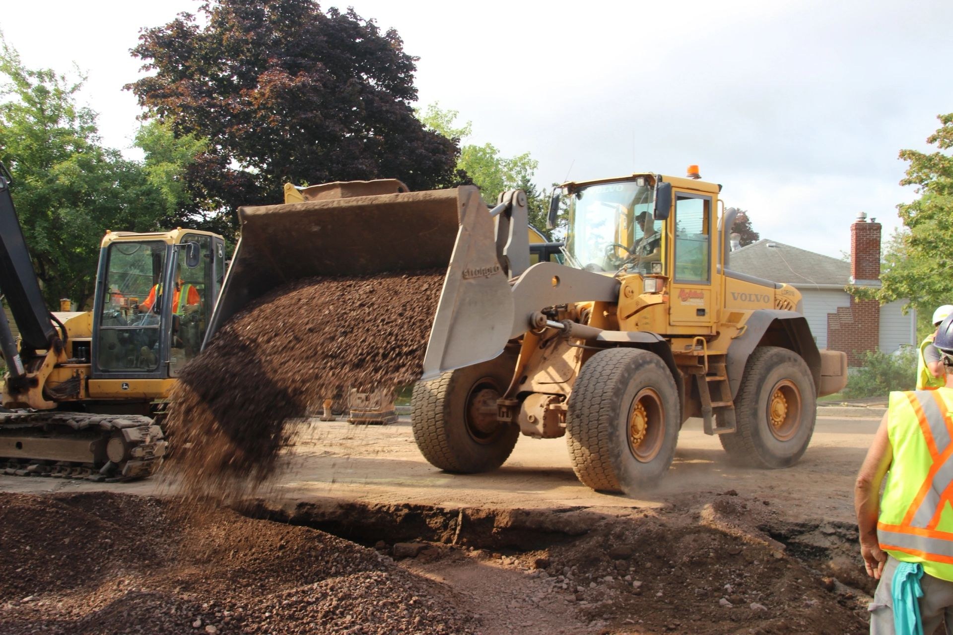 Volvo wheel loader pouring gravel bedding on a municipal street reconstruction