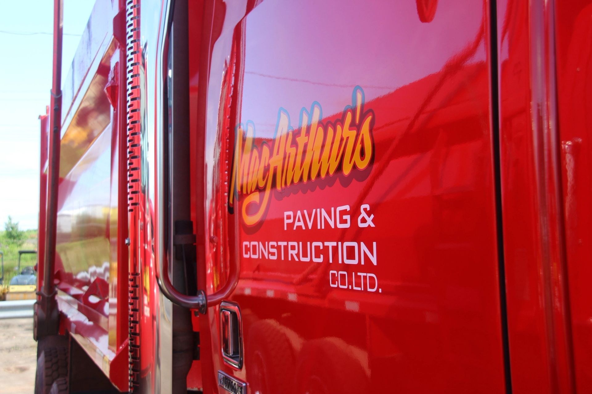 MacArthur's Paving & Construction lettering on the door of a red Kenworth dump truck