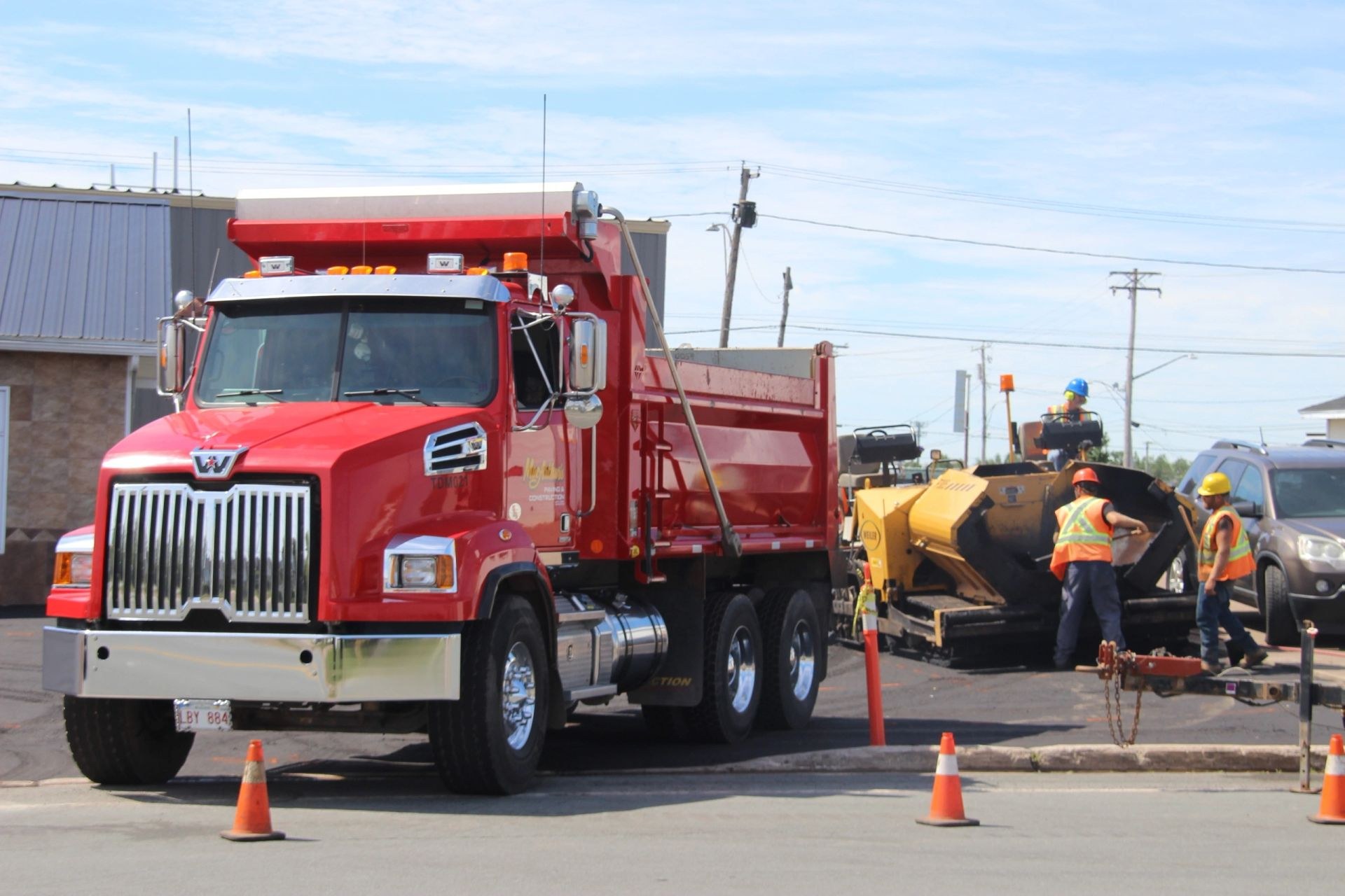 MacArthur's red dump truck feeding the paver on a commercial lot in Moncton
